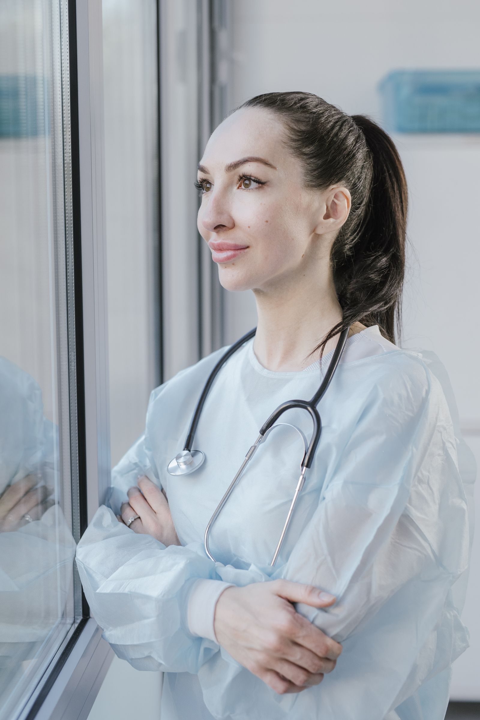 Nurse looking out a window, hopeful, seeing new possibilities